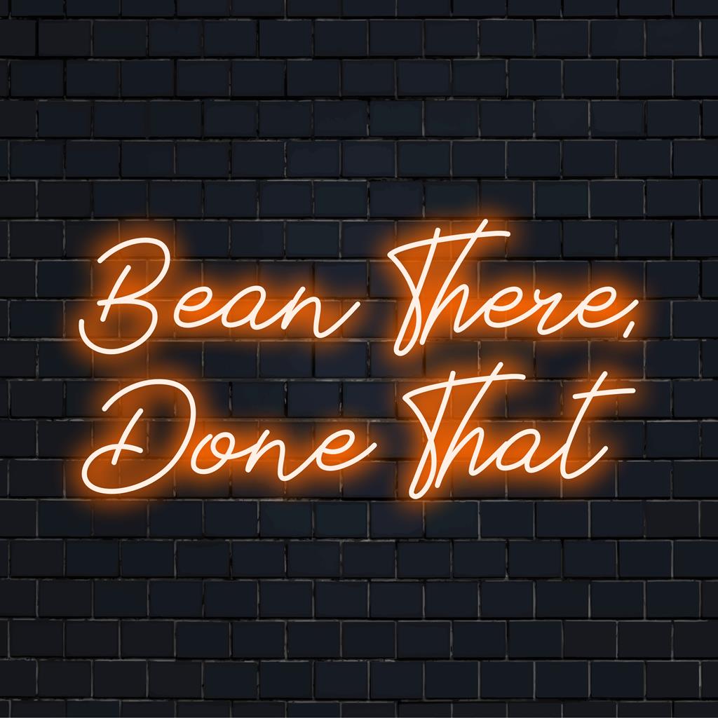 Vibrant LED neon sign reading Bean There, Done That, perfect for coffee lovers. Neon quote art for cafes or home decor.