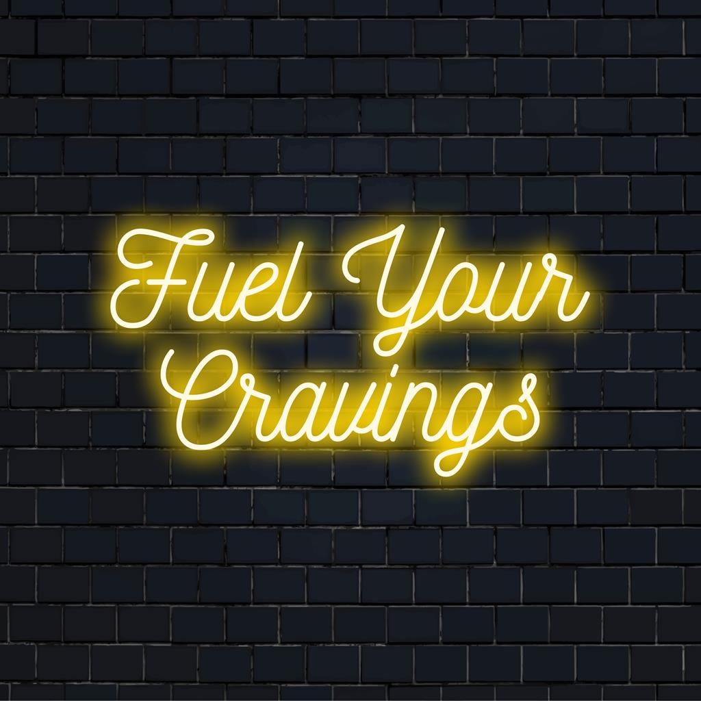 Brugerdefineret LED neonskilt med sætningen Fuel Your Cravings, med moderne typografisk design og livlige neonfarver.