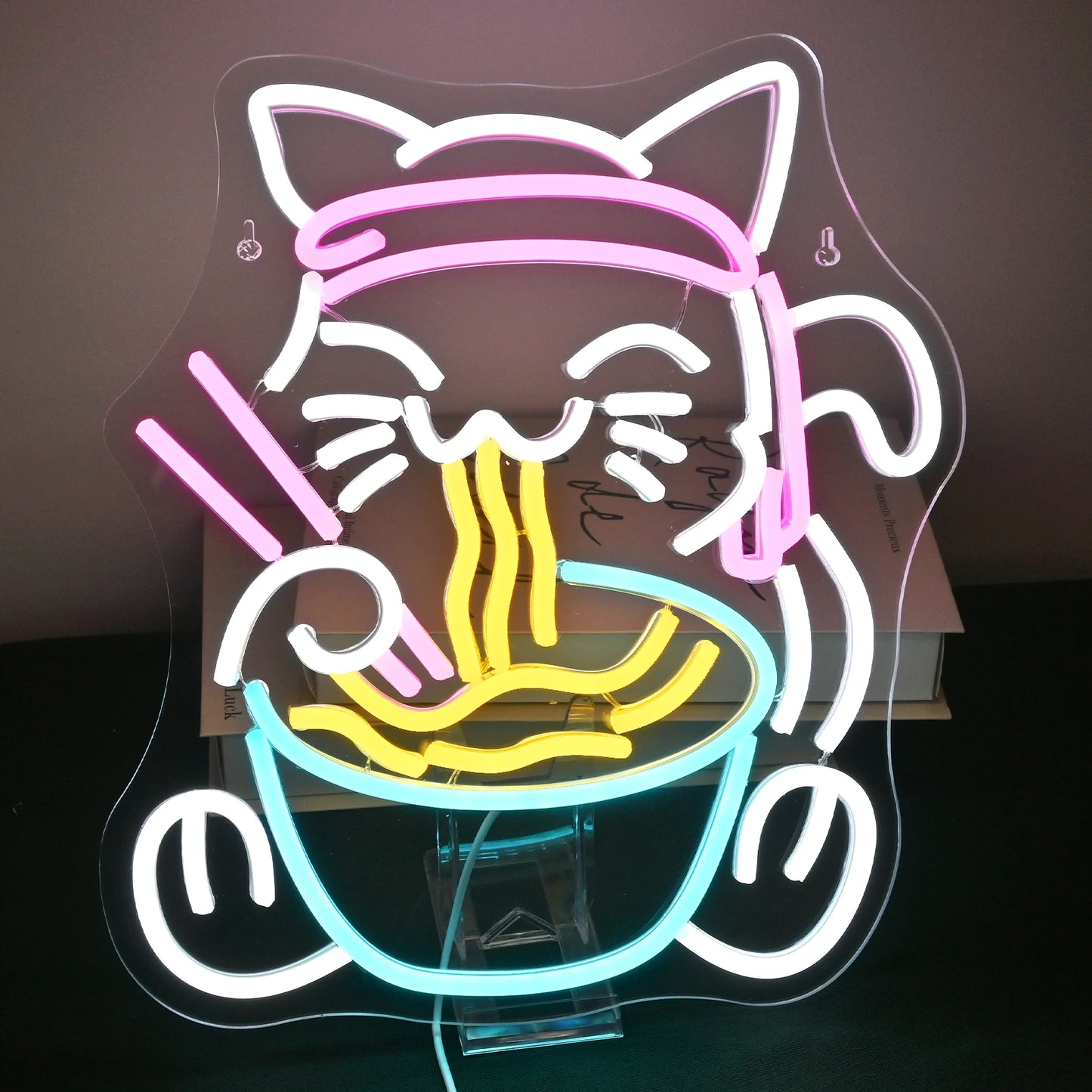 L'image présente un panneau néon LED vibrant et coloré représentant un design fantaisiste d'un chat savourant un bol de ramen.