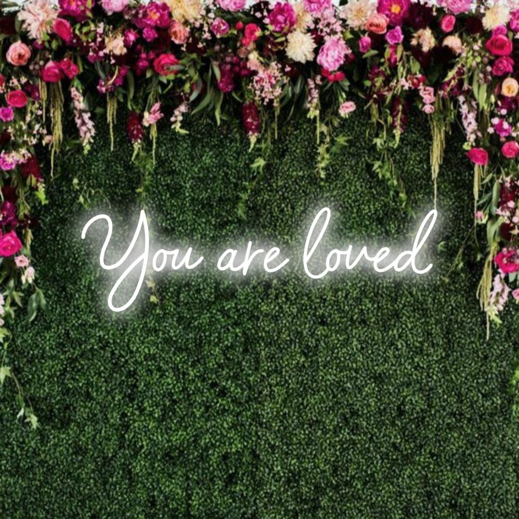 Un'insegna al neon LED personalizzata e vivace con il messaggio You Are Loved che illumina gli spazi con calore e incoraggiamento.