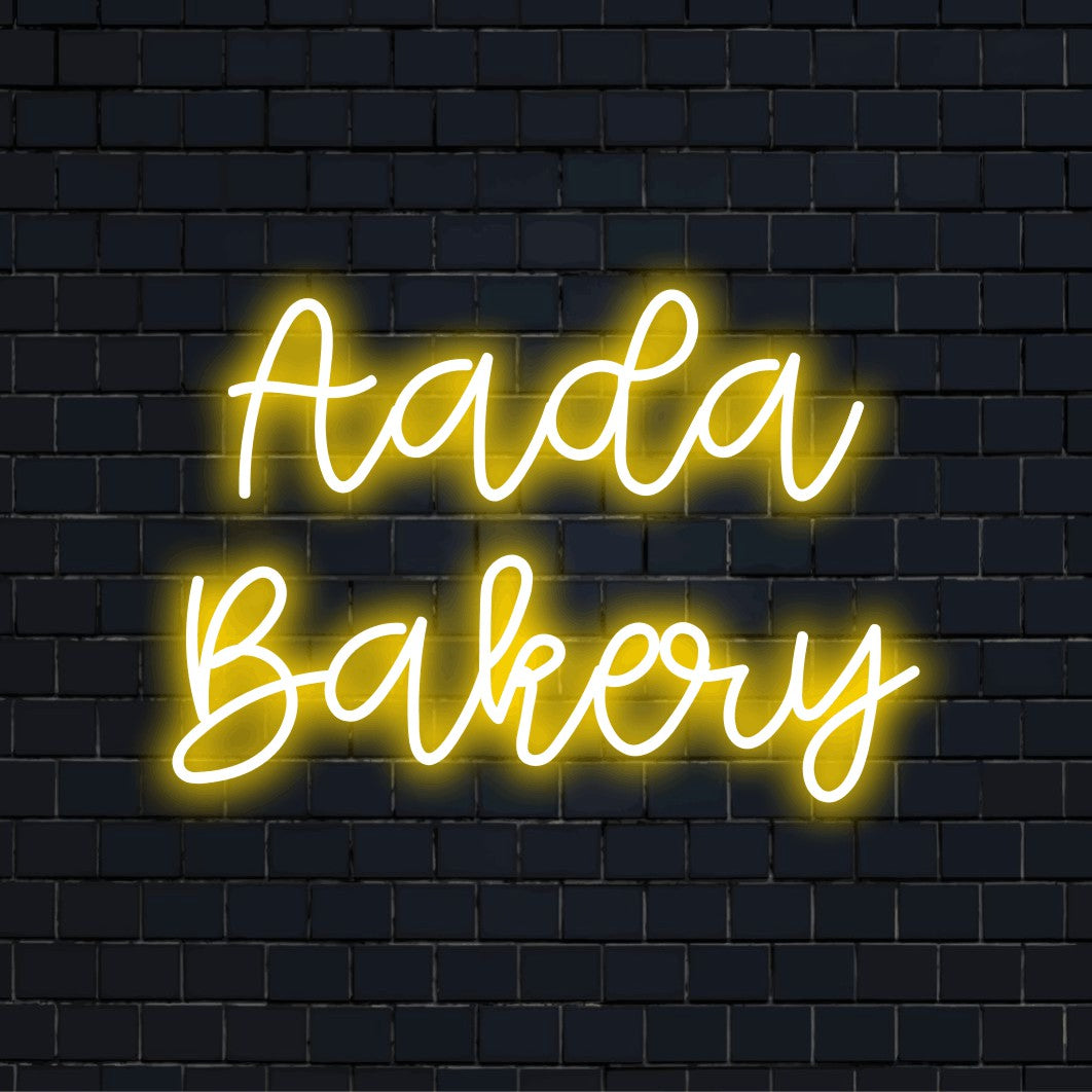 Aada Bakery Personalized LED Neon Sign, bright neon lettering on black brick background