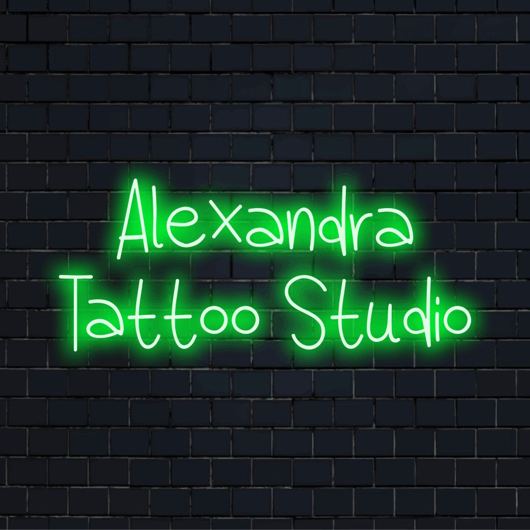 Alexandra Tattoo Studio Custom Name Neon Sign, soft neon glow against black brick wall