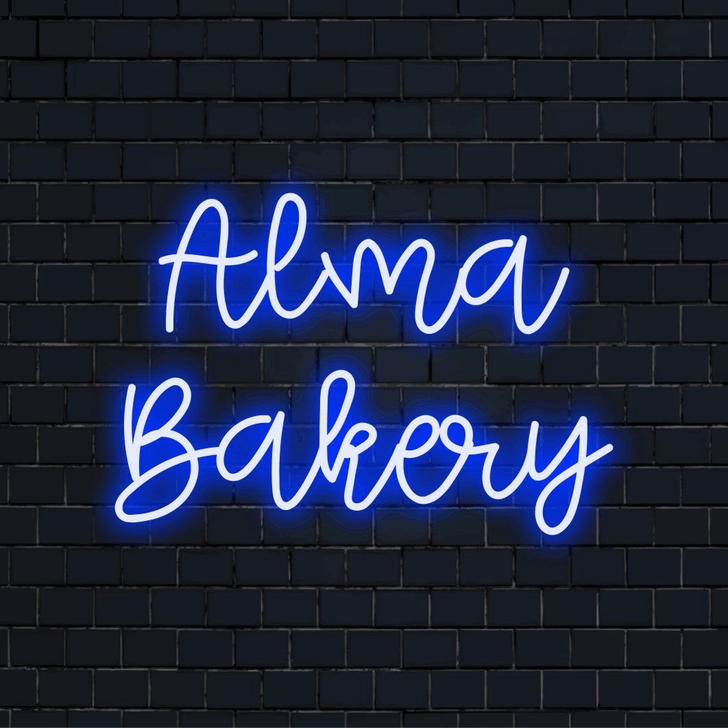 Alma Bakery Personalized Neon Light with soft neon glow against black brick wall