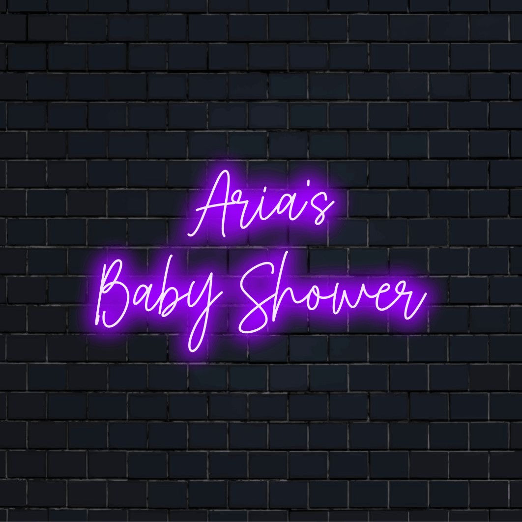 Aria_s Baby Shower Custom Name Neon Sign, glowing lettering against black brick wall