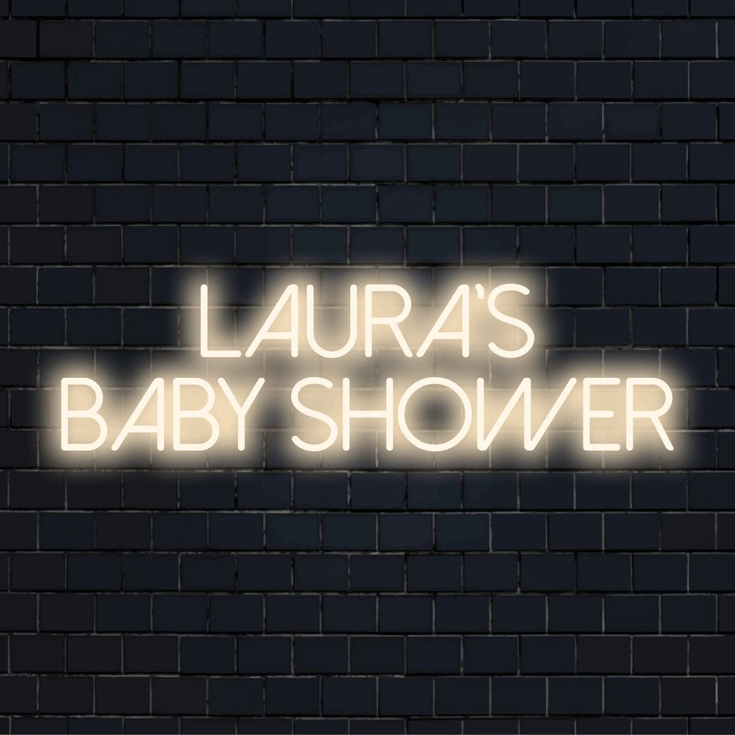Laura_s Baby Shower Personalized LED Neon Sign, glowing lettering against black brick wall