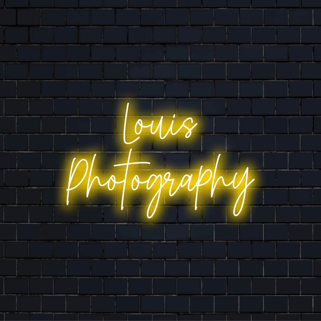 Louis Photography Custom Name Neon Sign, bright neon lettering against black brick wall