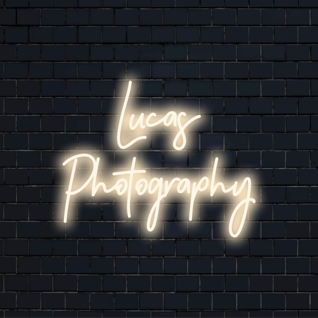 Lucas Photography Personalized LED Neon Sign, glowing neon text on dark brick wall