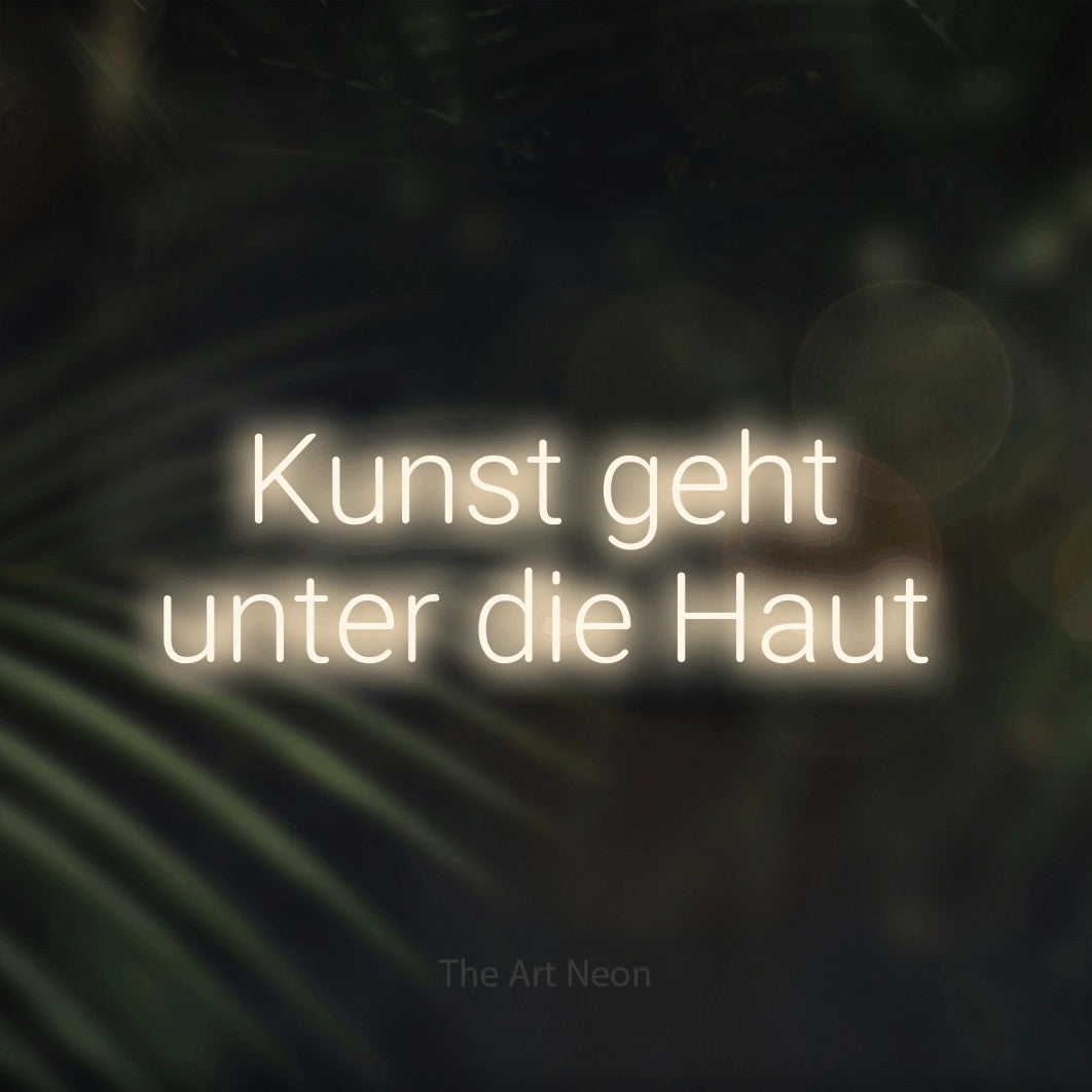 LED neon sign reading “Kunst geht unter die Haut”, arranged in 2 lines.
