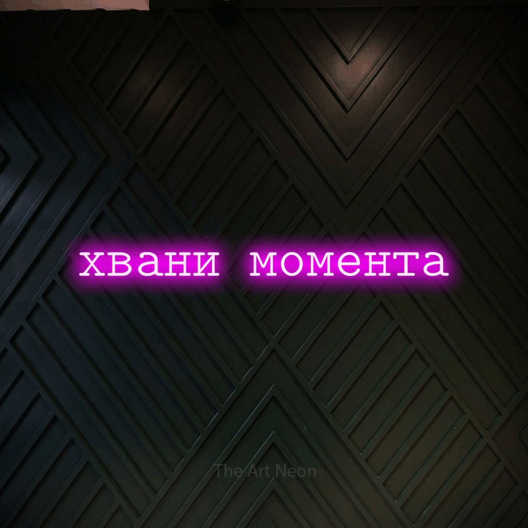 LED neon sign reading “хвани момента”, arranged in a single line.
