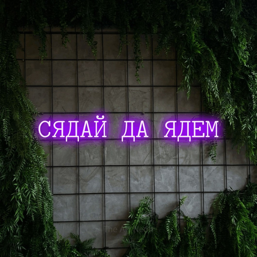 LED neon sign reading “СЯДАЙ ДА ЯДЕМ”, arranged in a single line.