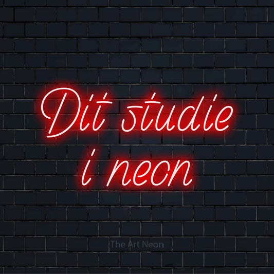 Personligt neonskilt med teksten “Dit studie i neon” på en sort murstensvæg