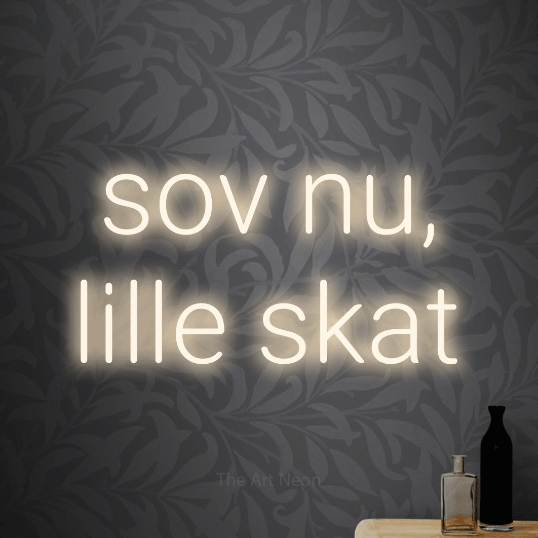 LED neon sign reading “sov nu, lille skat”, arranged in 2 lines.