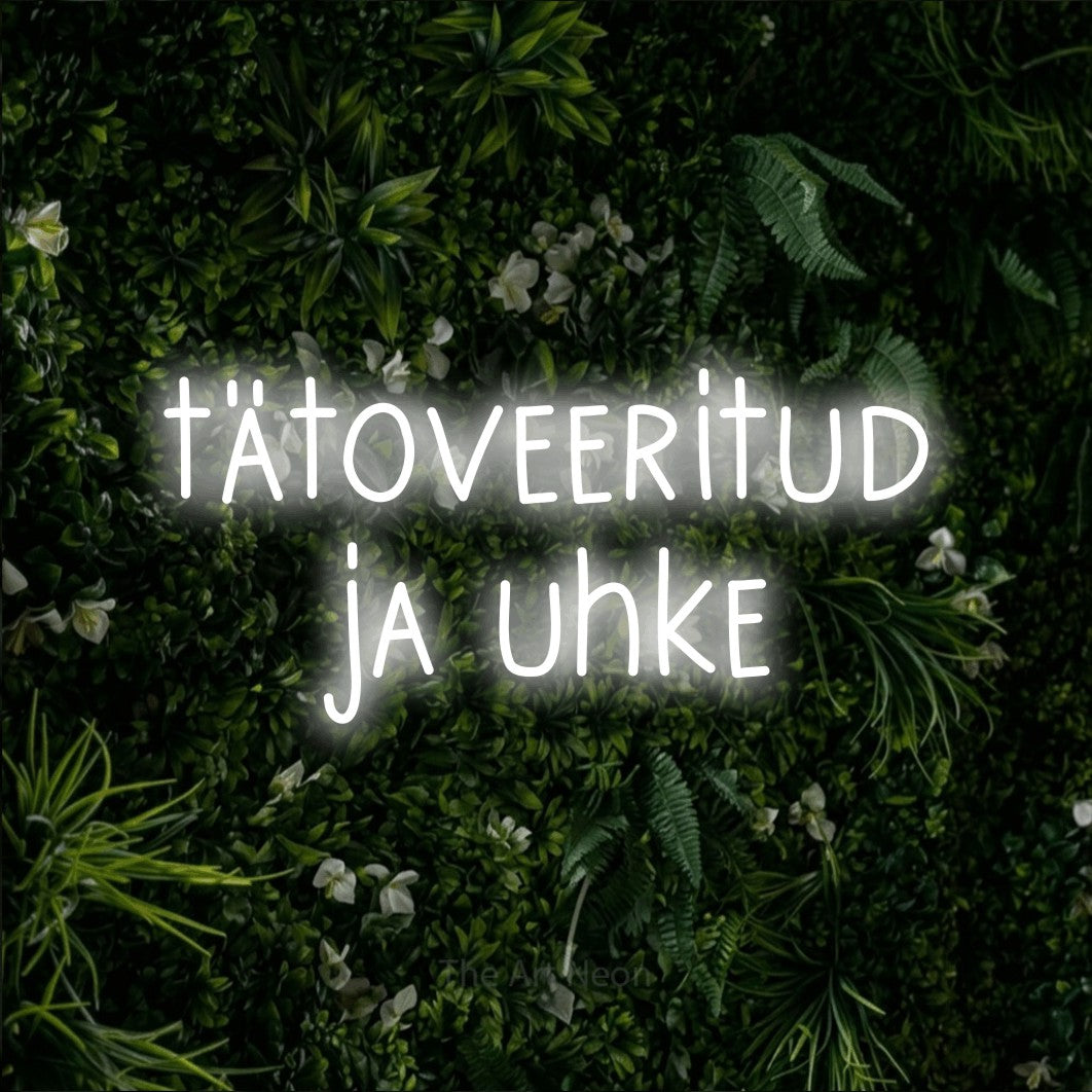 LED neon sign reading “tätoveeritud ja uhke”, arranged in two lines.