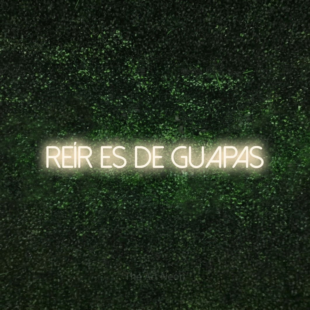 LED neon sign reading “Reír Es de Guapas”, arranged in a single line.