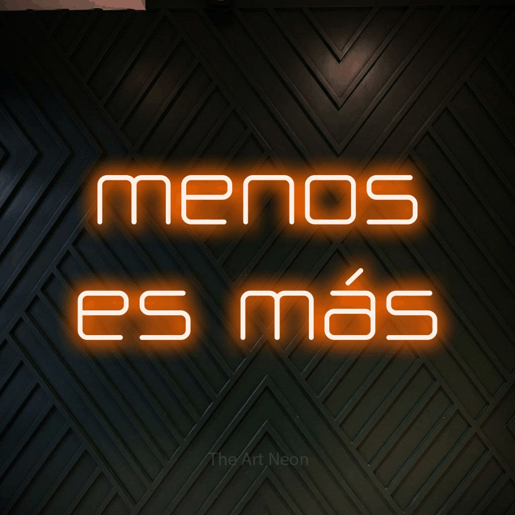 LED neon sign reading “menos es más”, arranged in 2 lines.