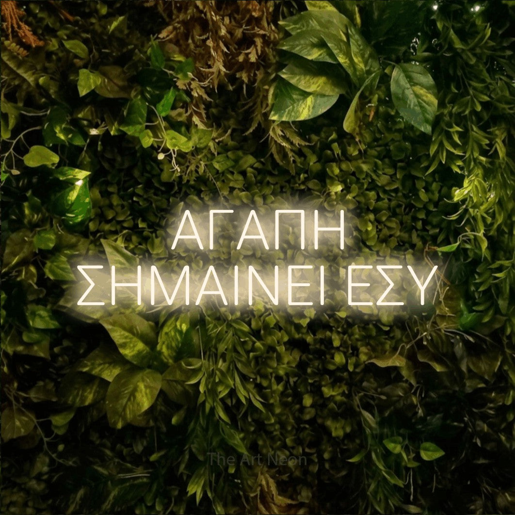 LED neon sign reading “ΑΓΑΠΗ ΣΗΜΑΙΝΕΙ ΕΣΥ”, arranged in two lines.