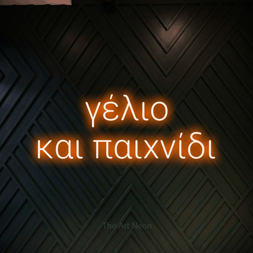 LED neon sign reading “γέλιο και παιχνίδι”, arranged in two lines.