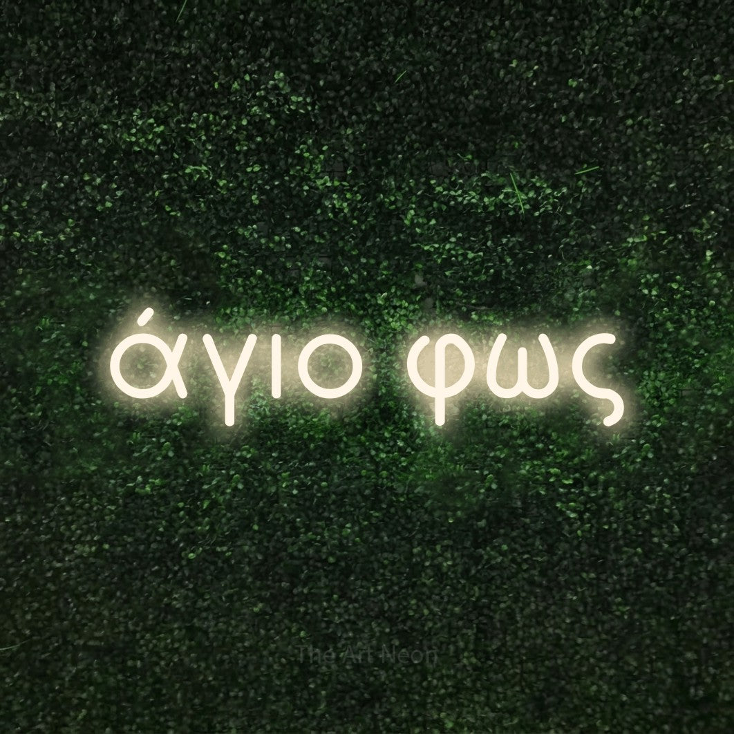 LED neon sign reading “άγιο φως”, arranged in a single line.