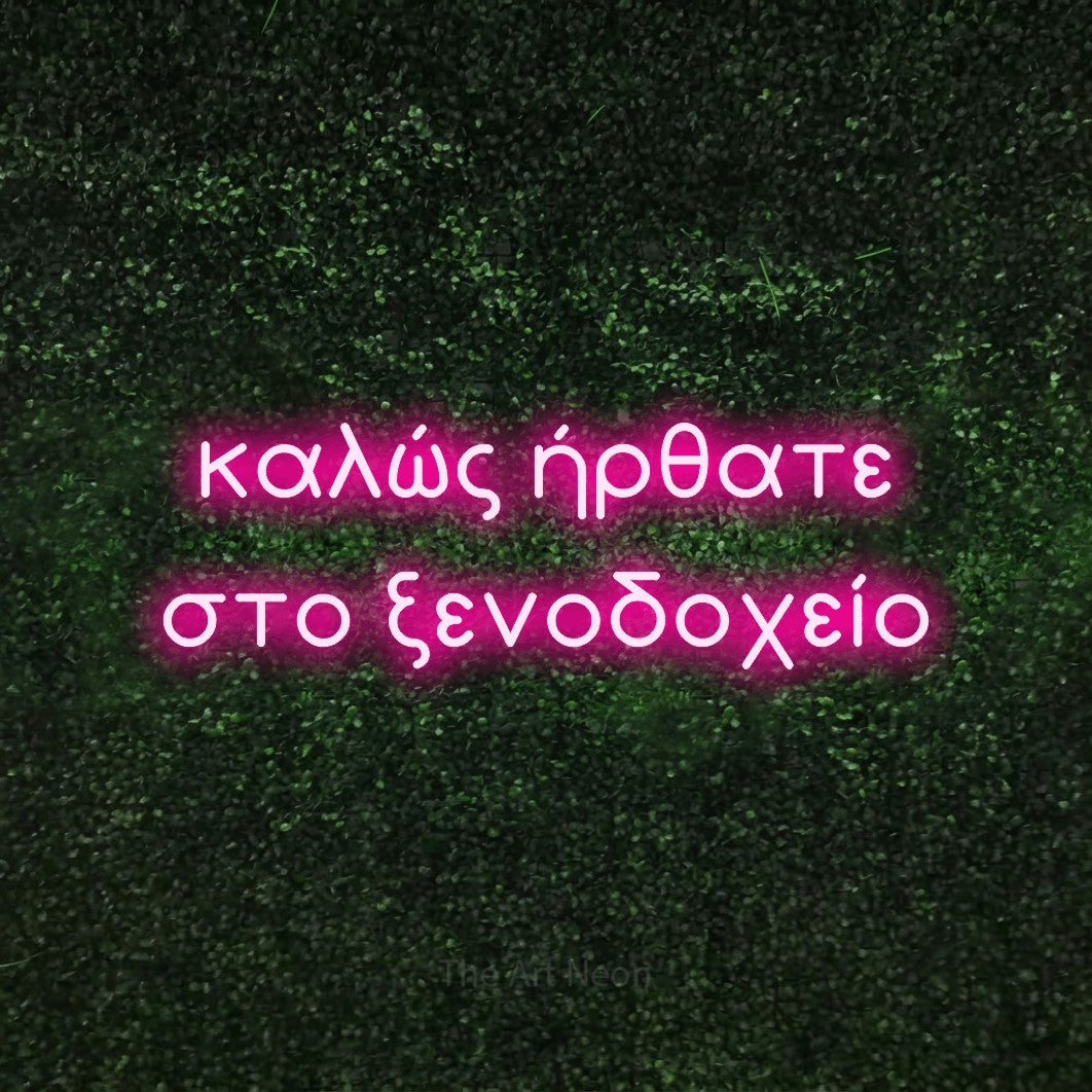 LED neon sign reading “καλώς ήρθατε στο ξενοδοχείο”, arranged in two lines.