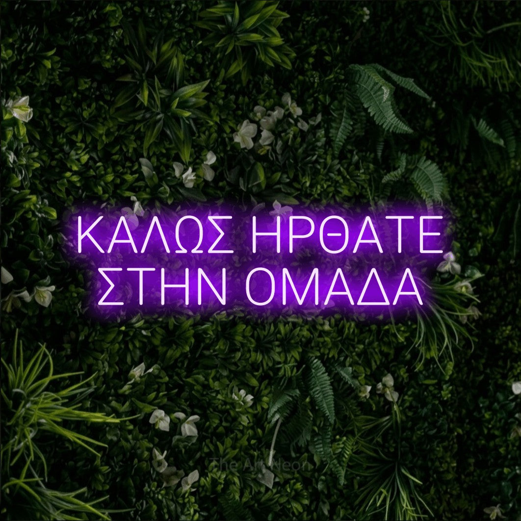 LED neon sign reading “ΚΑΛΩΣ ΗΡΘΑΤΕ ΣΤΗΝ ΟΜΑΔΑ”, arranged in two lines.