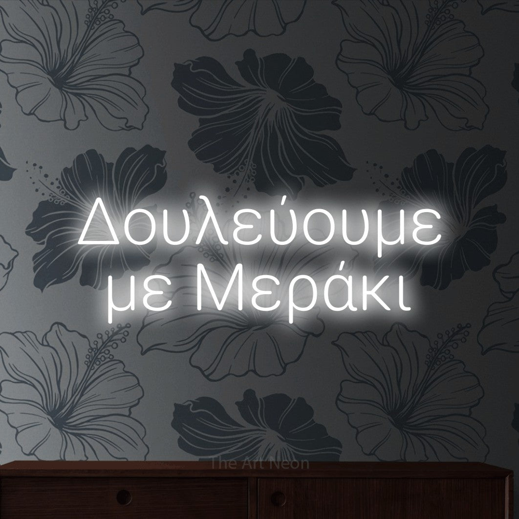 LED neon sign reading “Δουλεύουμε με Μεράκι”, arranged in two lines.