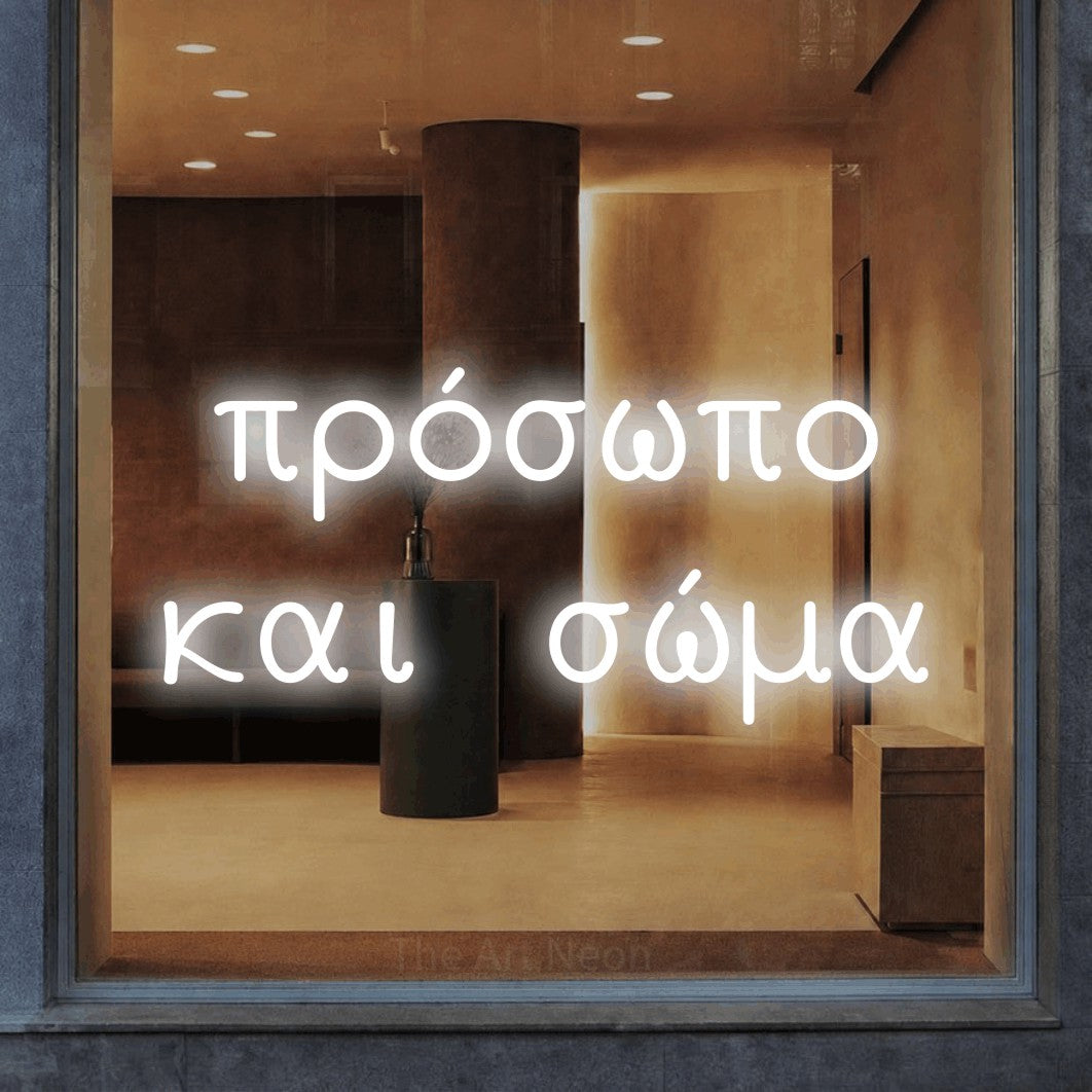 LED neon sign reading “πρόσωπο και σώμα”, arranged in two lines.