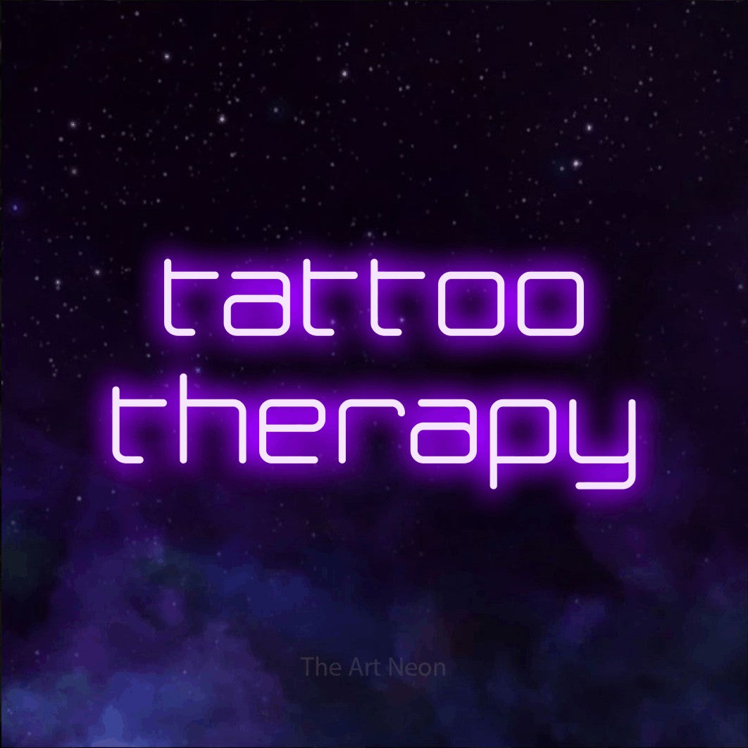 LED neon sign reading “tattoo therapy”, arranged in two lines.