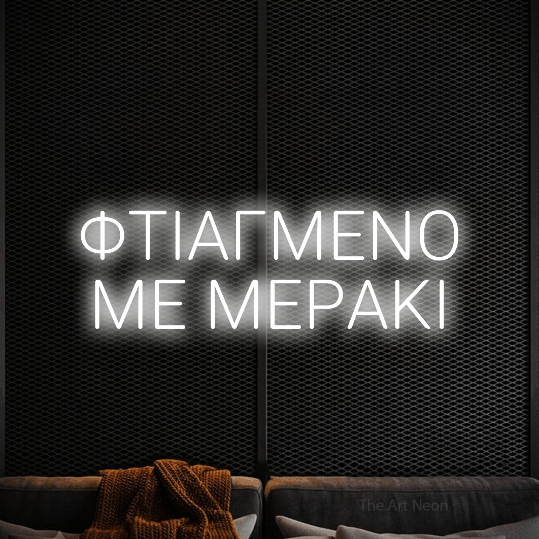 LED neon sign reading “ΦΤΙΑΓΜΕΝΟ ΜΕ ΜΕΡΑΚΙ”, arranged in two lines.