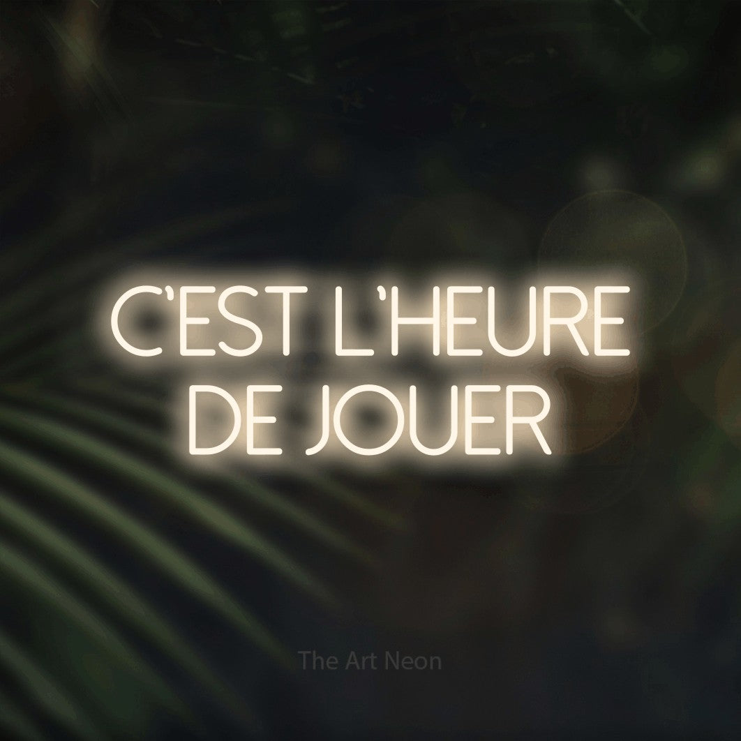LED neon sign reading “C'est l'heure de jouer”, arranged in 2 lines.