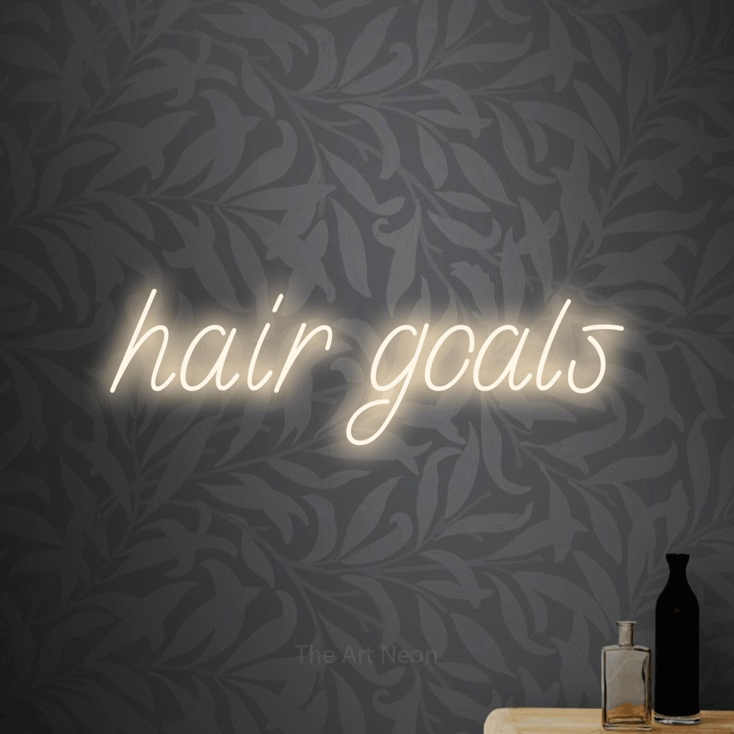 LED neon sign reading “hair goals”, arranged in a single line.
