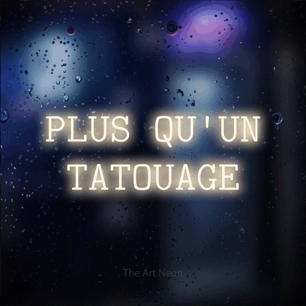 LED neon sign reading “PLUS QU'UN TATOUAGE”, arranged in 2 lines.