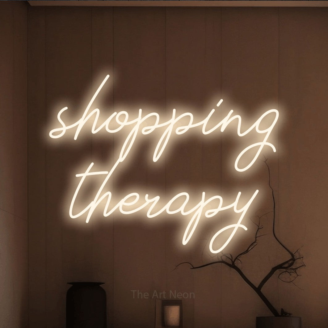 LED neon sign reading “shopping therapy”, arranged in 2 lines.
