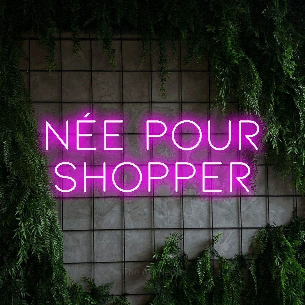 LED neon sign reading “née pour SHOPPER”, arranged in 2 lines.