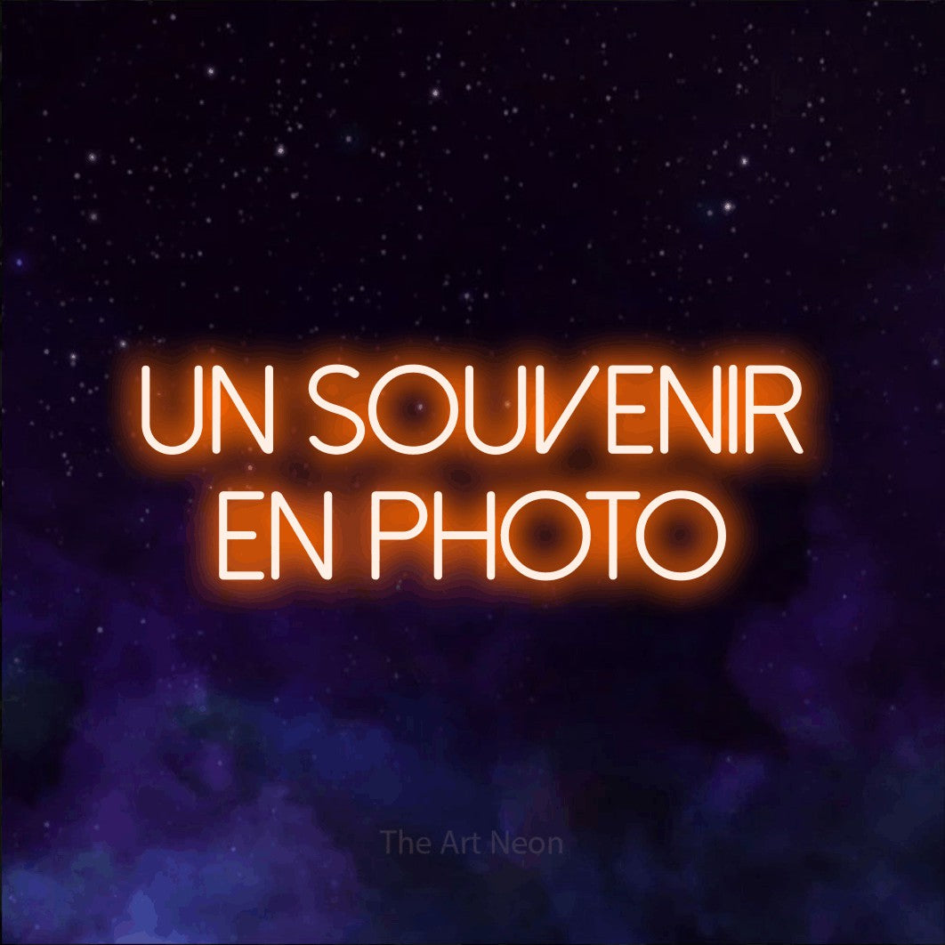 LED neon sign reading “un souvenir en photo”, arranged in 2 lines.