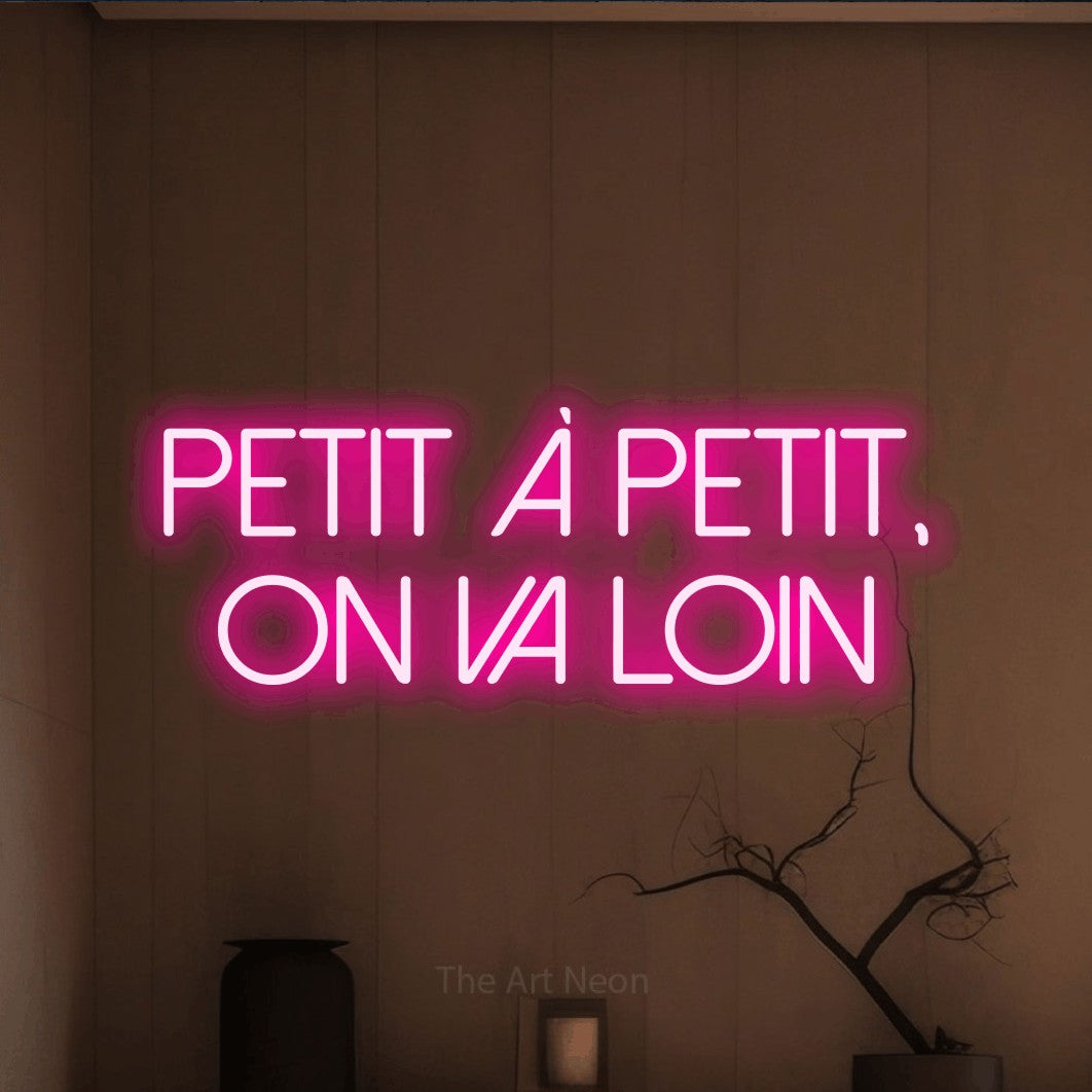 LED neon sign reading “Petit À Petit, On Va Loin”, arranged in 2 lines.