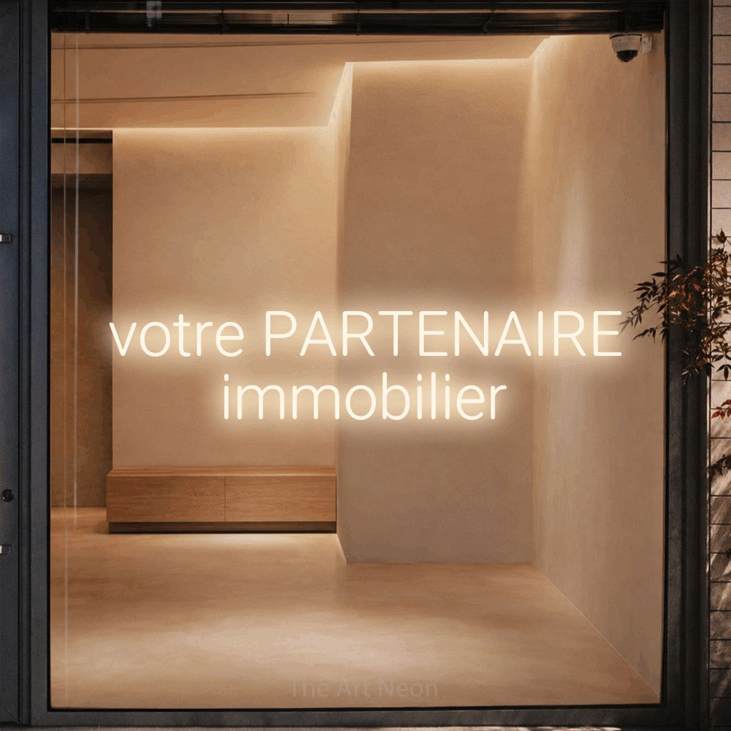 LED neon sign reading “votre PARTENAIRE immobilier”, arranged in 2 lines.