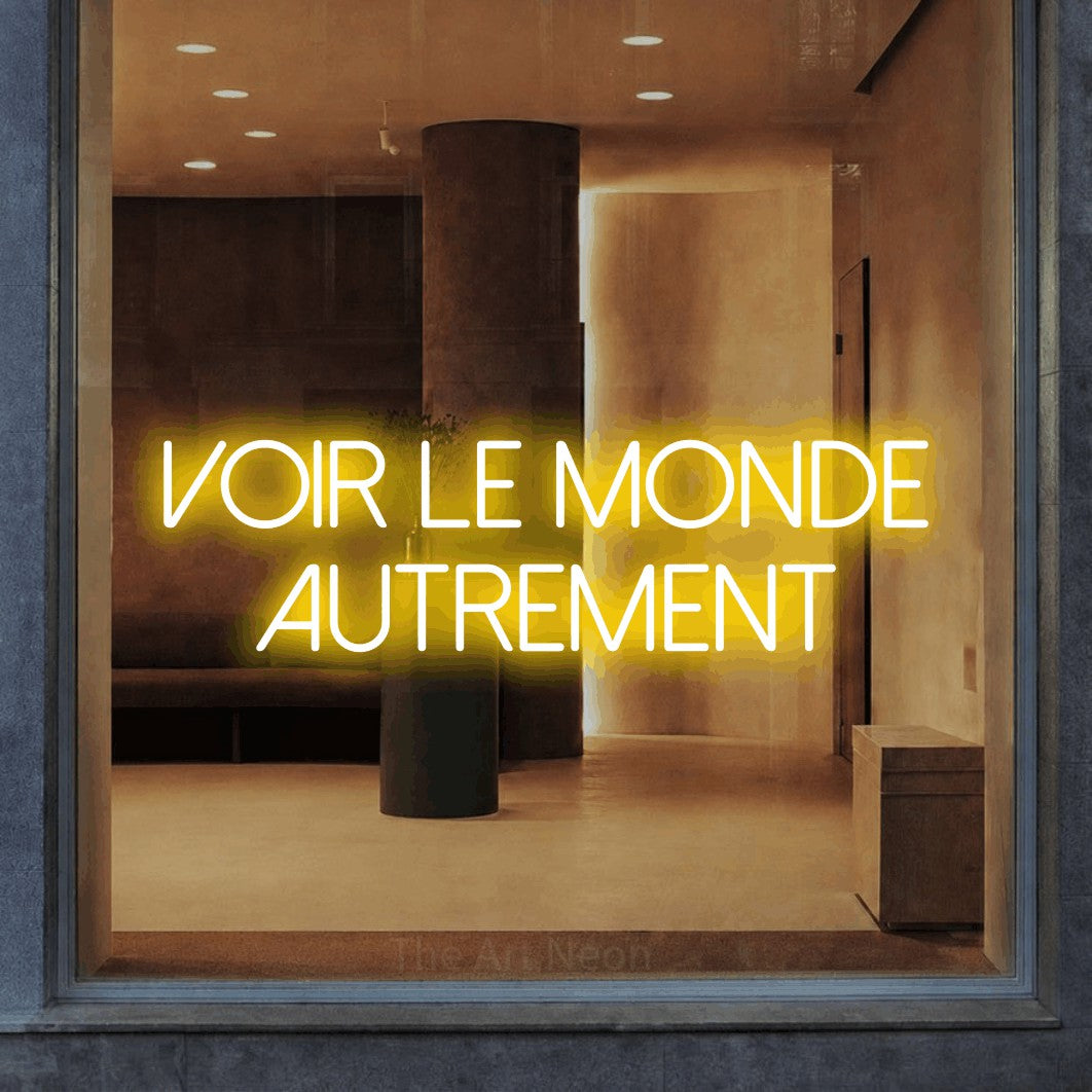 LED neon sign reading “voir le monde autrement”, arranged in 2 lines.