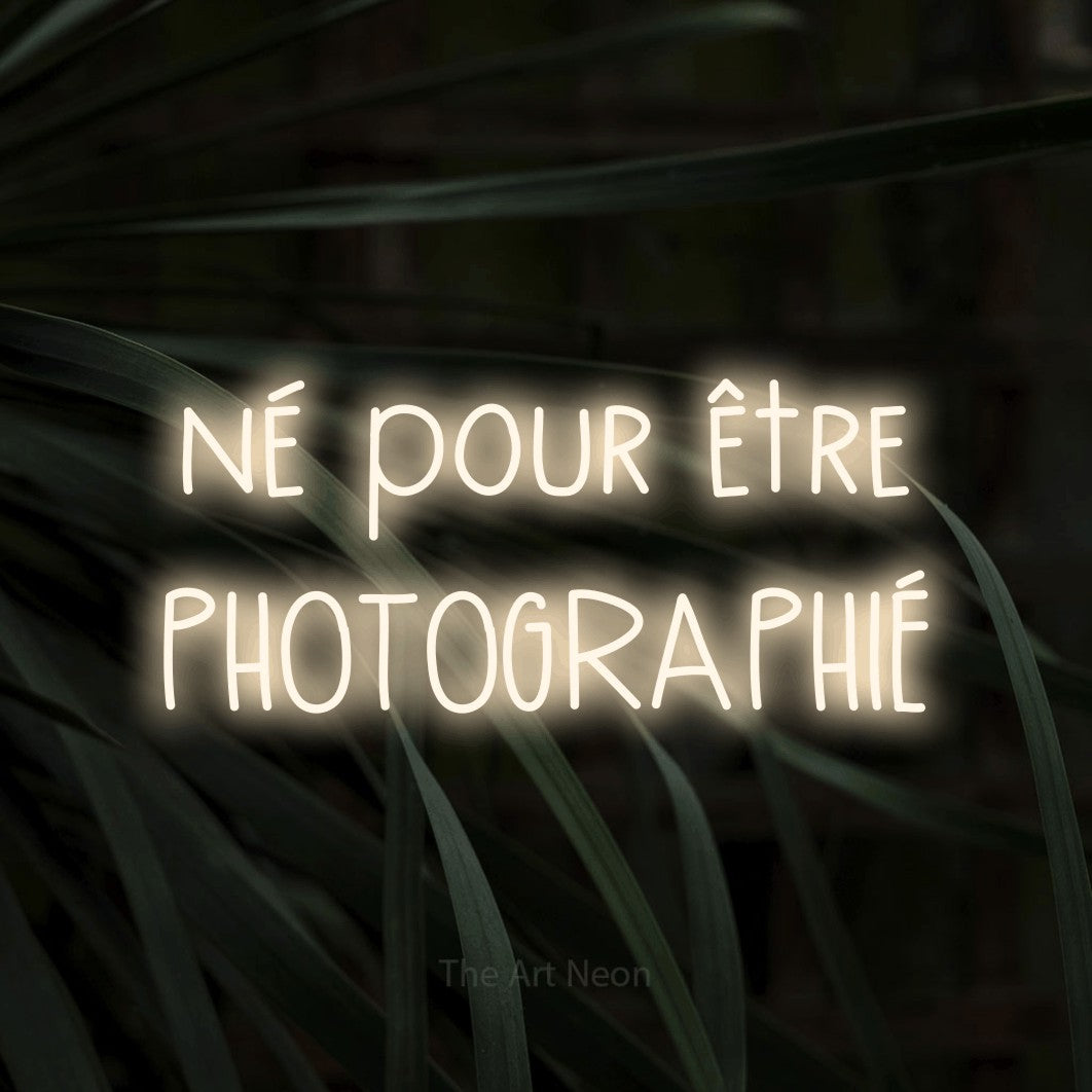 LED neon sign reading “né pour être PHOTOGRAPHIÉ”, arranged in 2 lines.