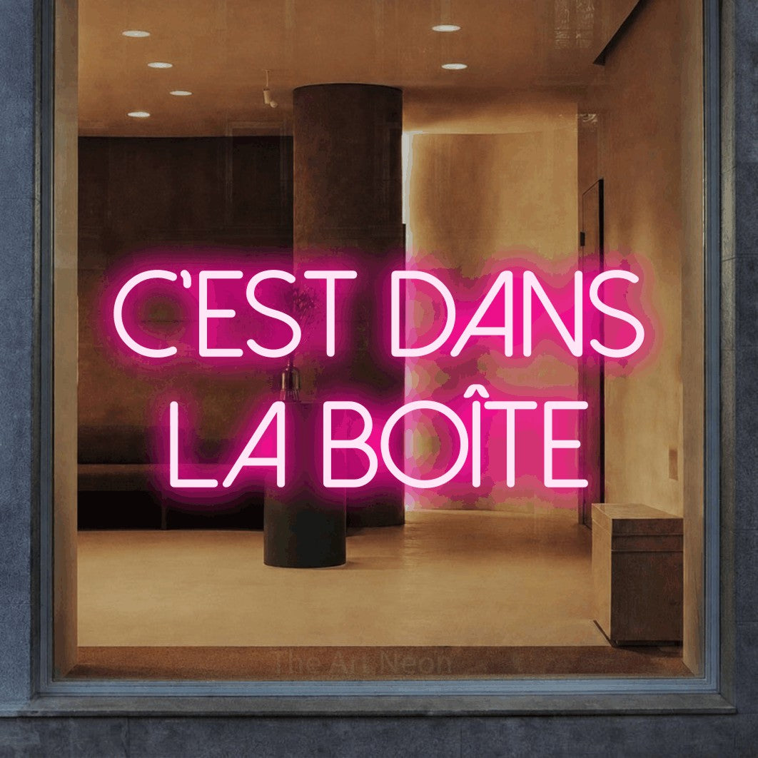 LED neon sign reading “C'est dans la boîte”, arranged in 2 lines.