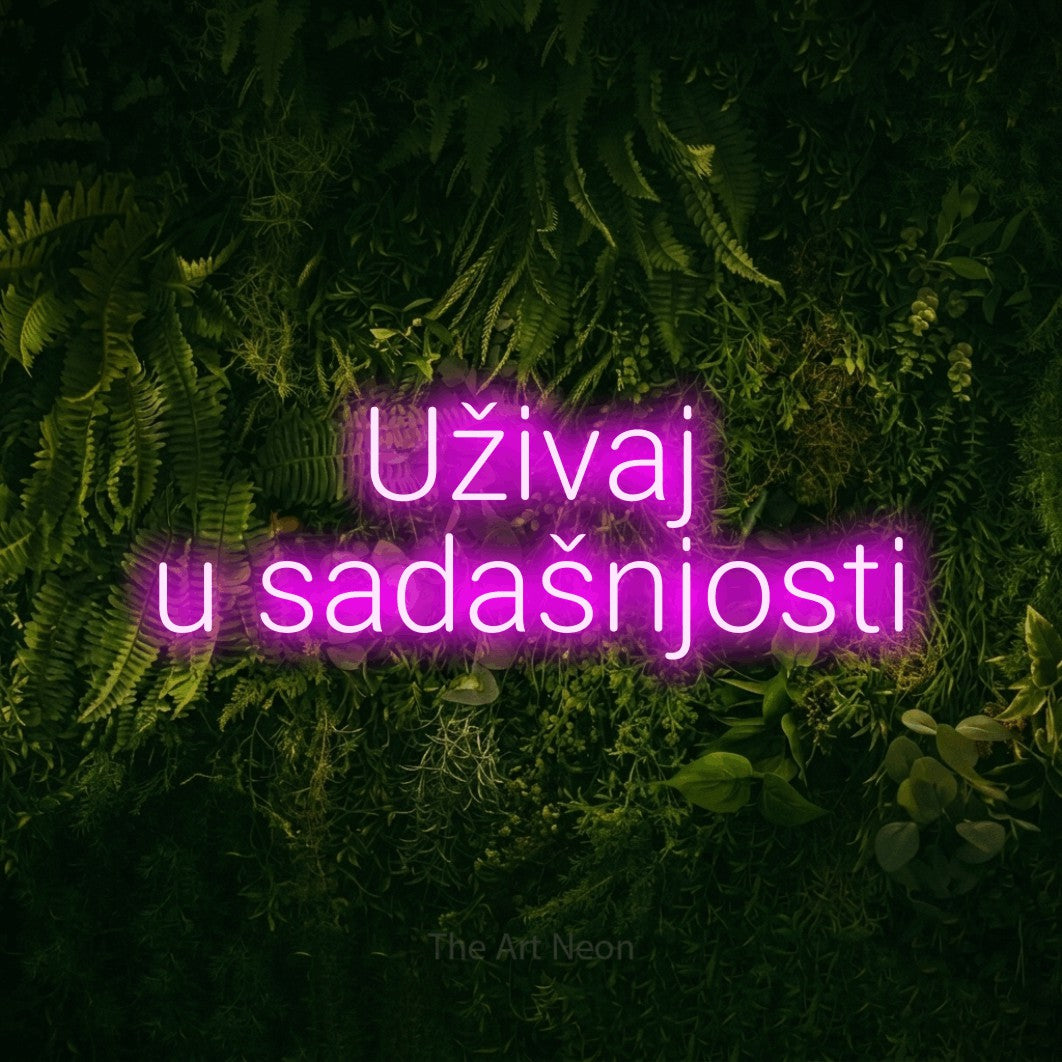 LED neon sign reading “Uživaj u sadašnjosti”, arranged in two lines.