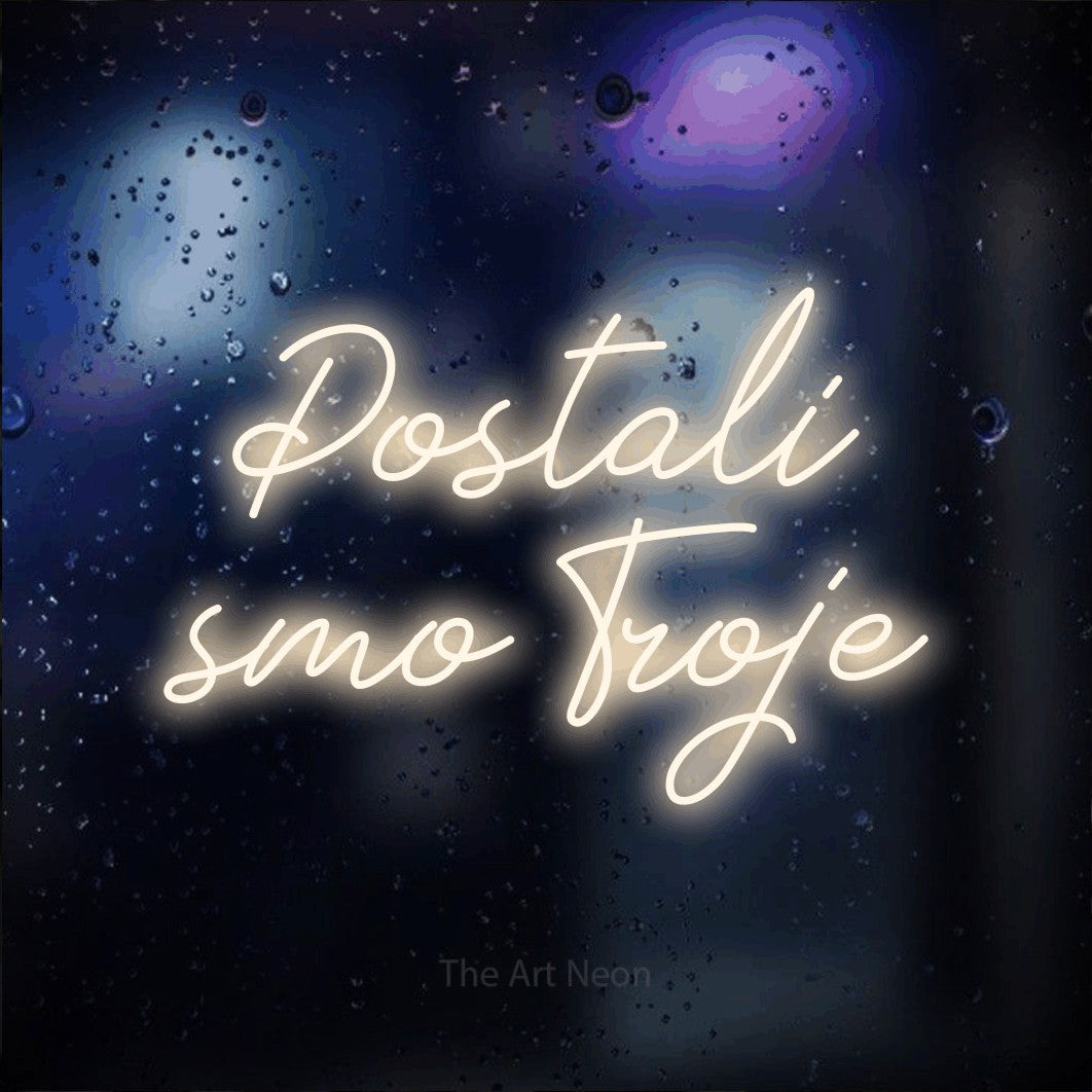 LED neon sign reading “Postali smo Troje”, arranged in two lines.