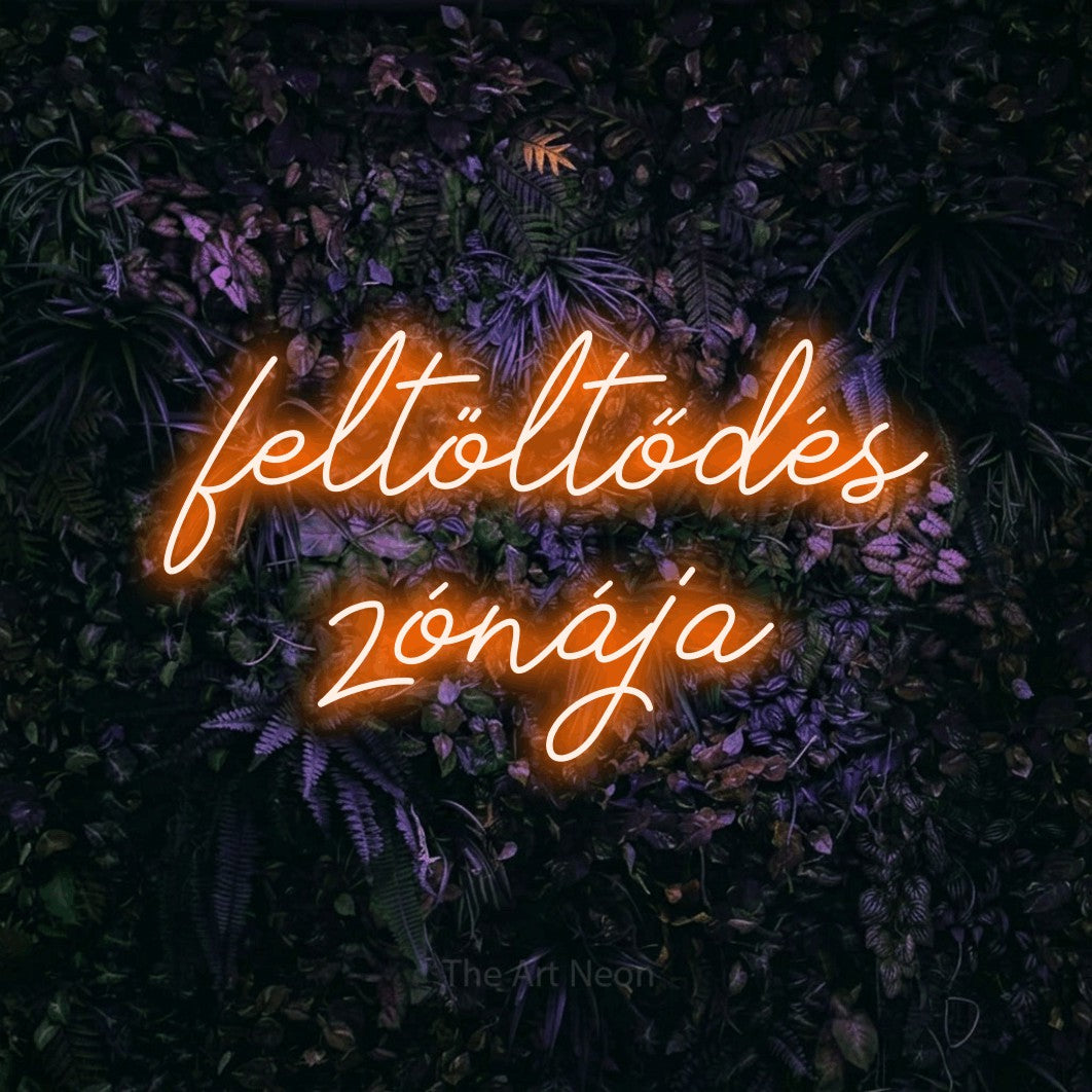 LED neon sign reading “feltöltődés zónája”, arranged in two lines.