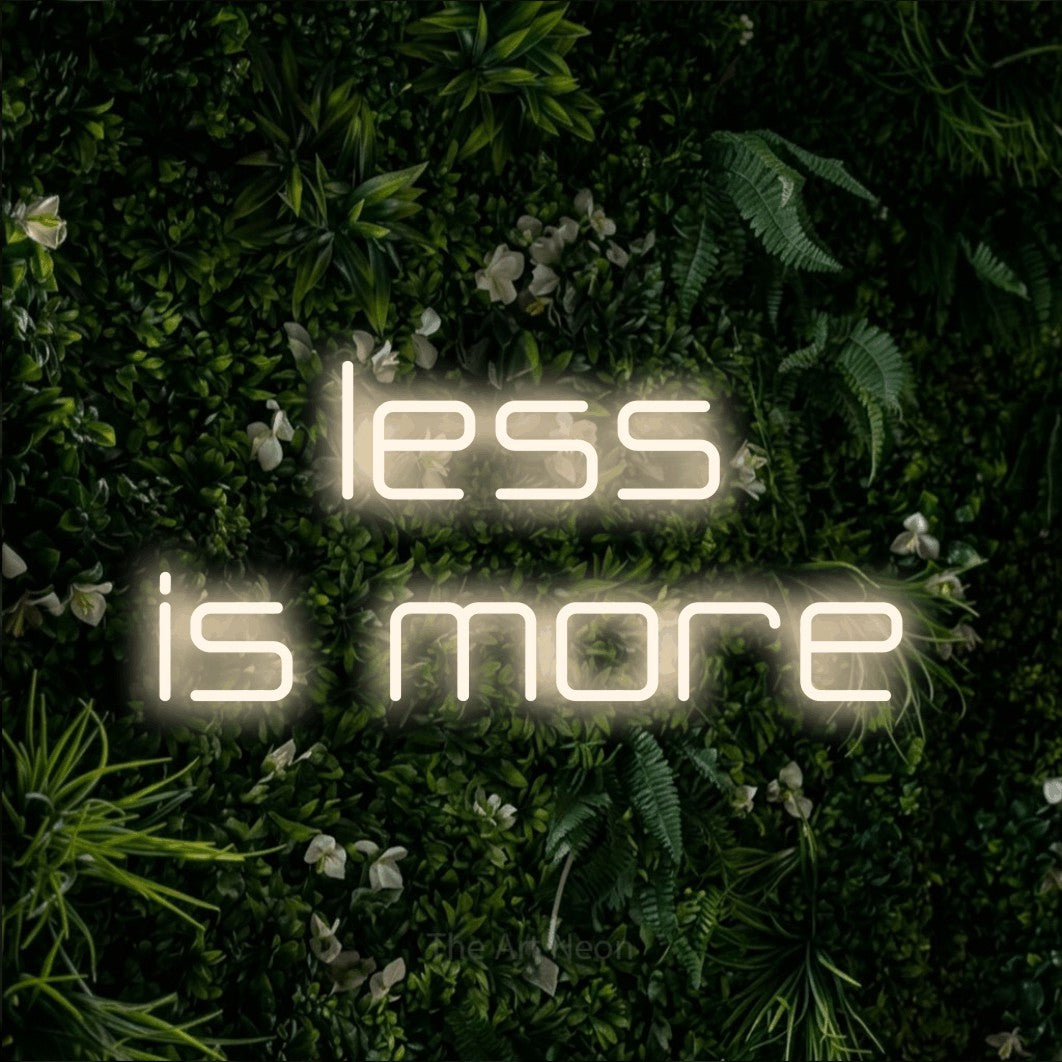 LED neon sign reading “less is more”, arranged in two lines.