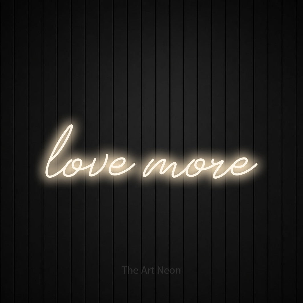 LED neon sign reading “love more”, arranged in a single line.