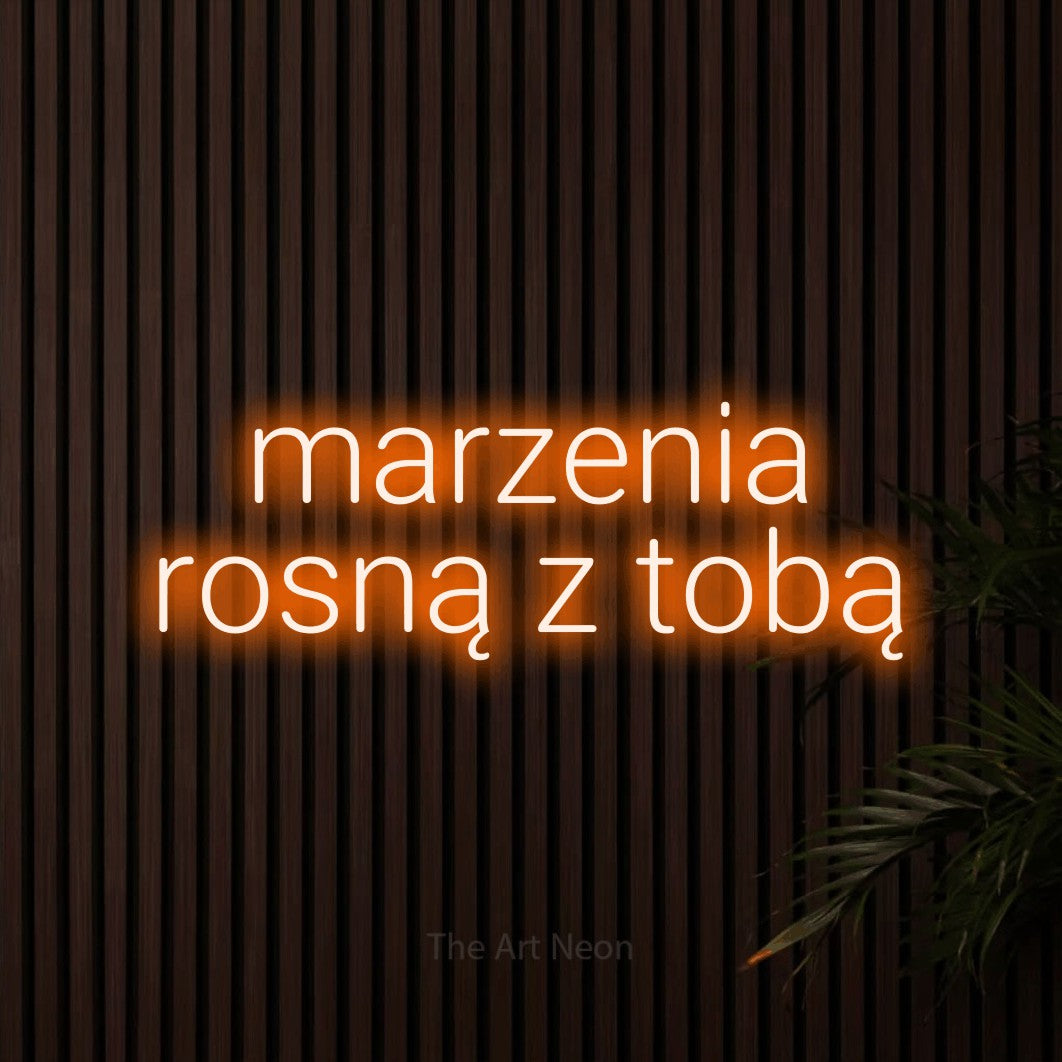 LED neon sign reading “marzenia rosną z tobą”, arranged in two lines.
