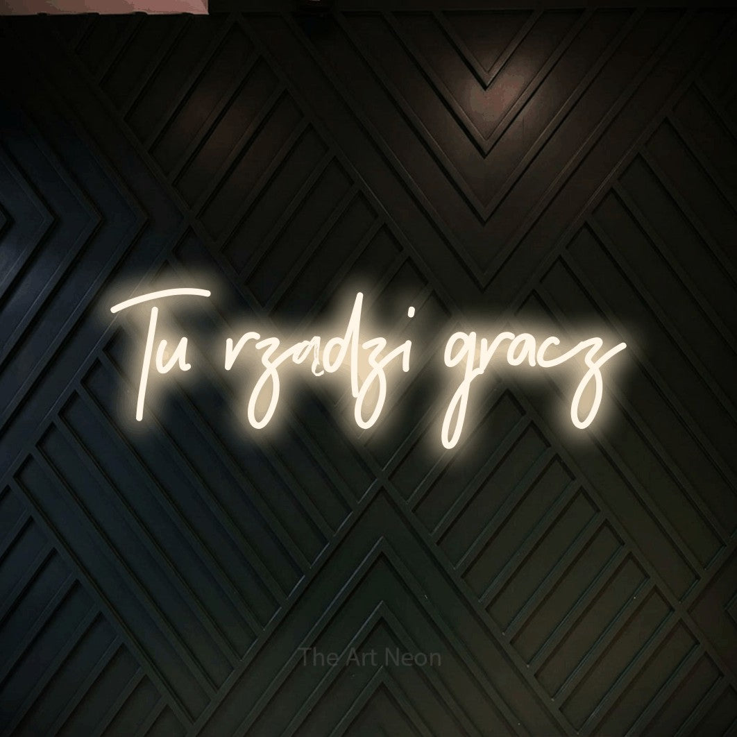 LED neon sign reading “Tu rządzi gracz”, arranged in a single line.