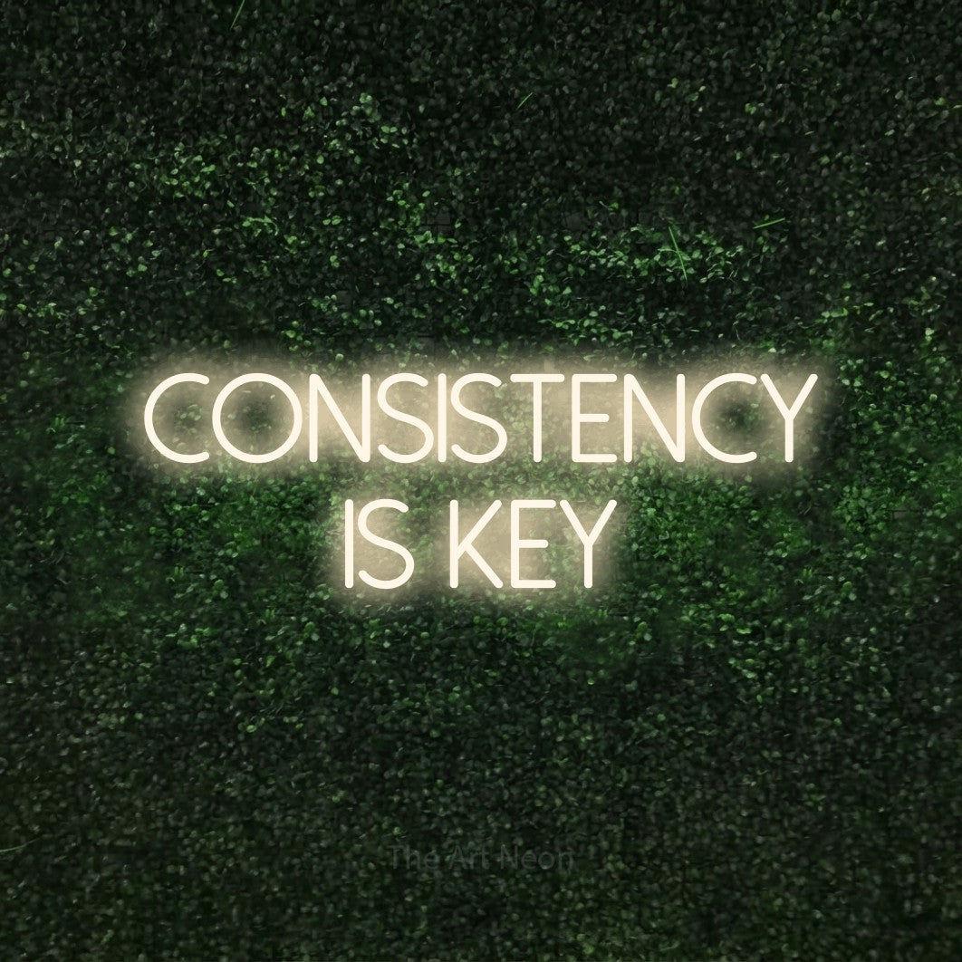 LED neon sign reading “Consistency Is Key”, arranged in two lines.