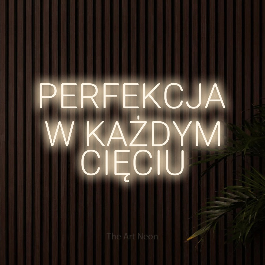 LED neon sign reading “PERFEKCJA W KAŻDYM CIĘCIU”, arranged in three lines.