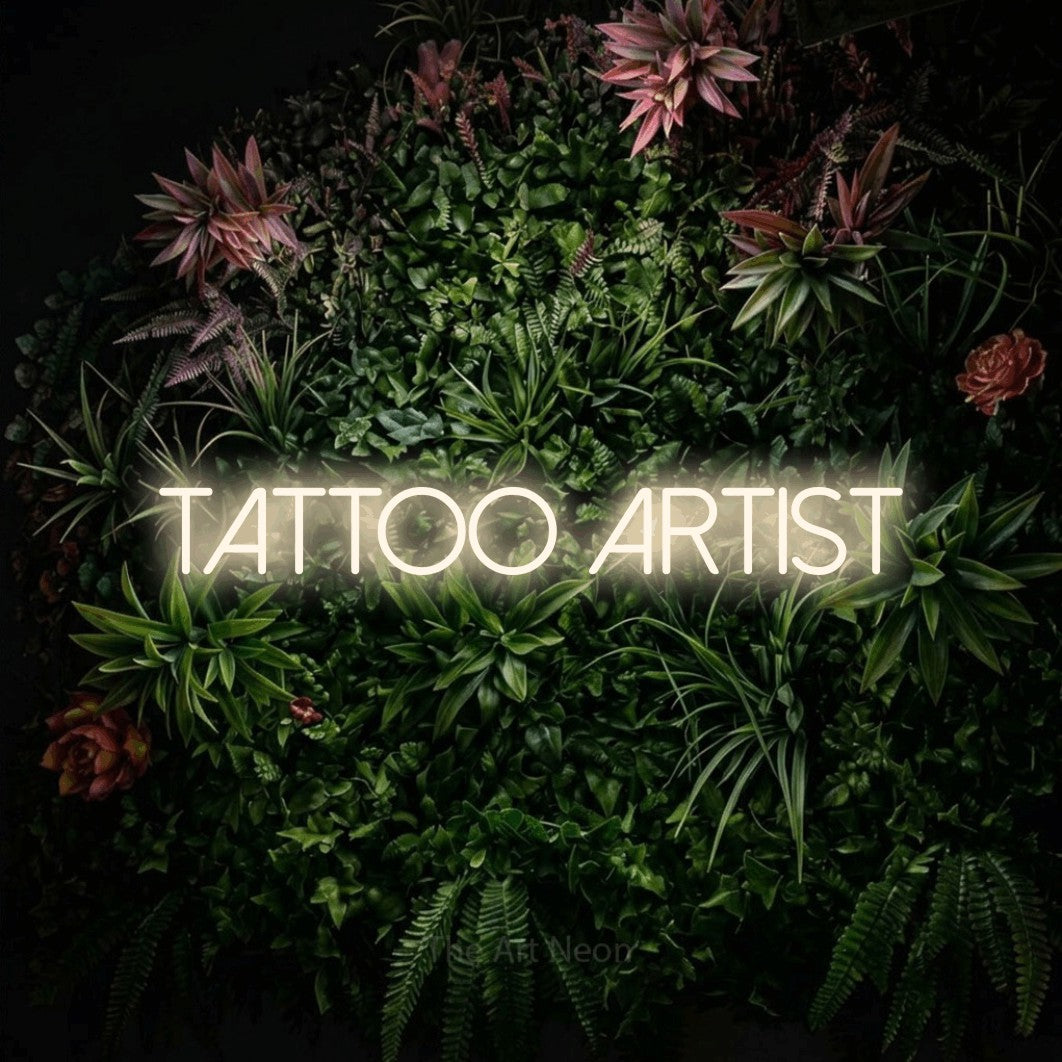 LED neon sign reading “tattoo artist”, arranged in a single line.