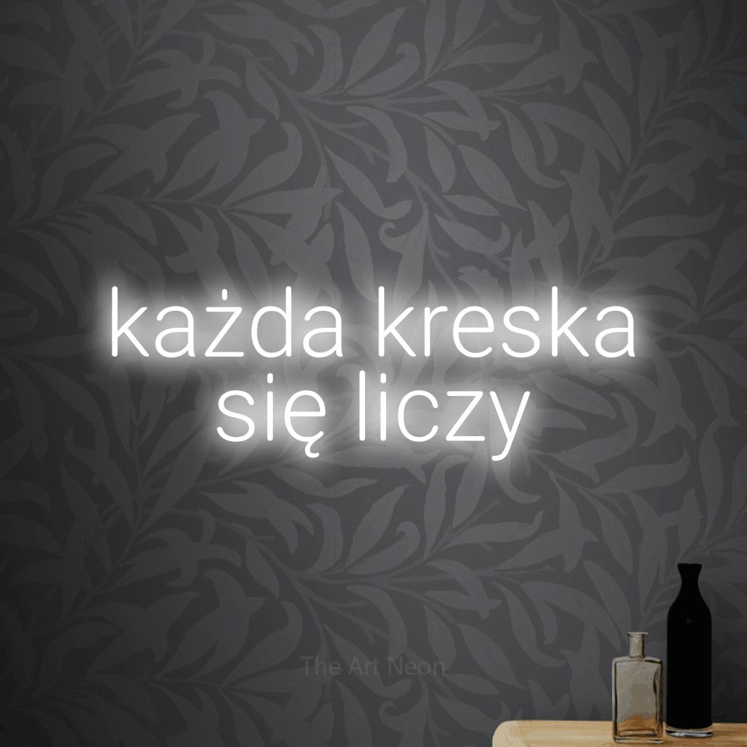 LED neon sign reading “każda kreska się liczy”, arranged in two lines.